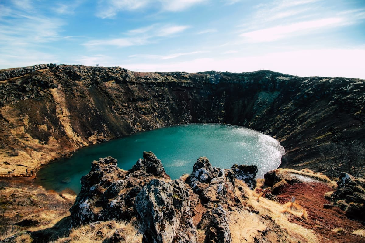 Vivid teal volcanic crater lake surrounded by dark rock walls, Iceland highlands