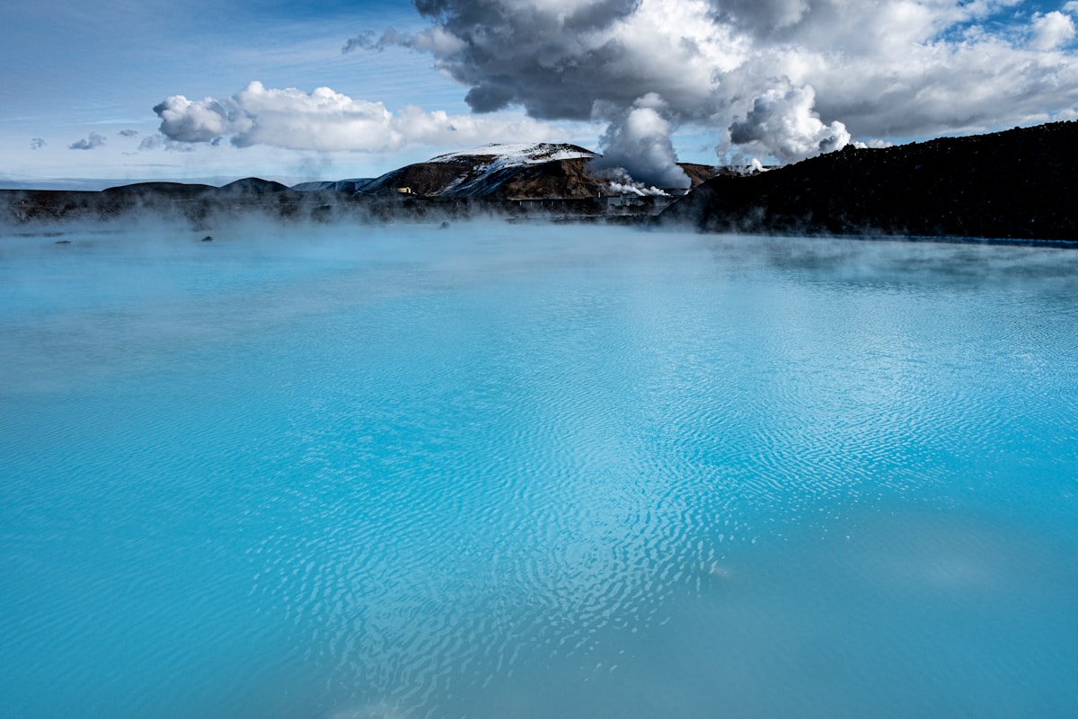 Steaming electric-blue geothermal lagoon under a dramatic cloudy sky at the Blue Lagoon, Iceland
