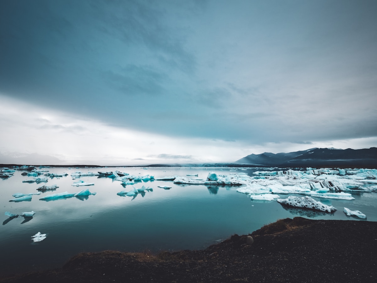 Ice bergs floating in Jökulsárlón glacial lagoon with mountains in background, south Iceland