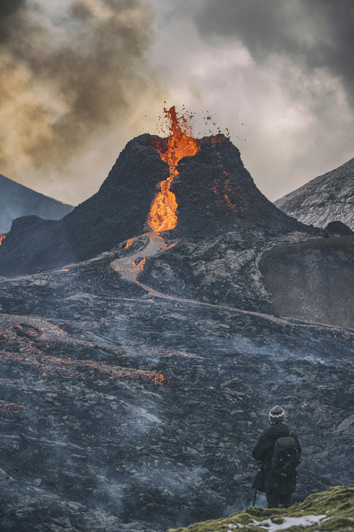 Person watching Fagradalsfjall volcano erupt with lava flow, Reykjanes Peninsula, Iceland
