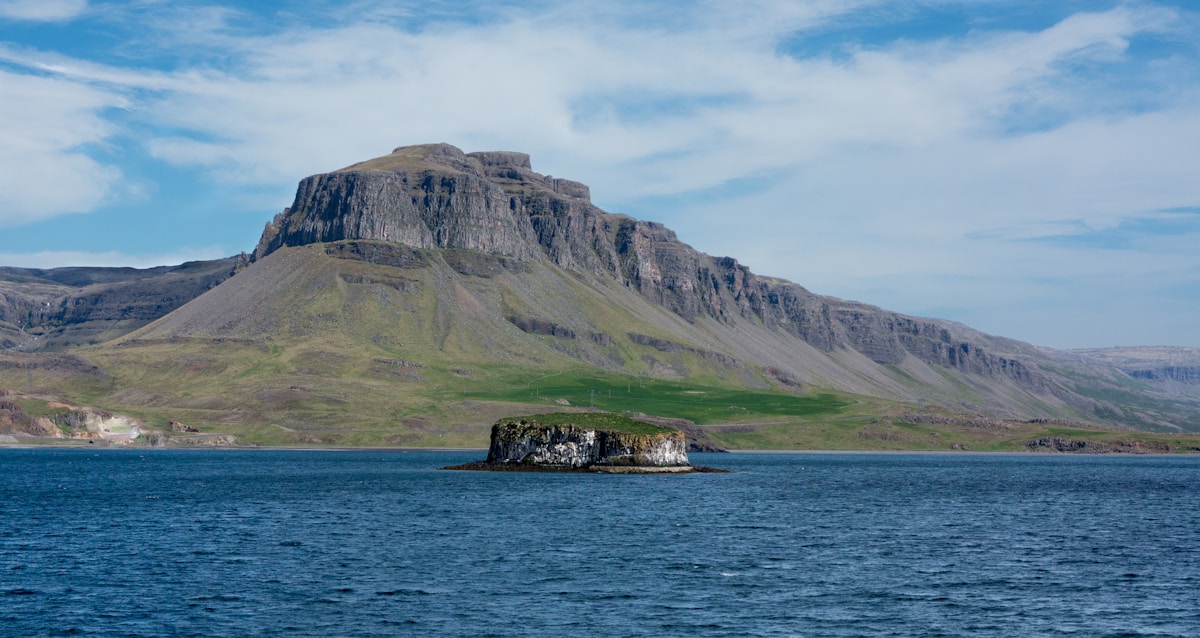 Green and brown mountain beside calm fjord water, Hvalfjörður, west Iceland