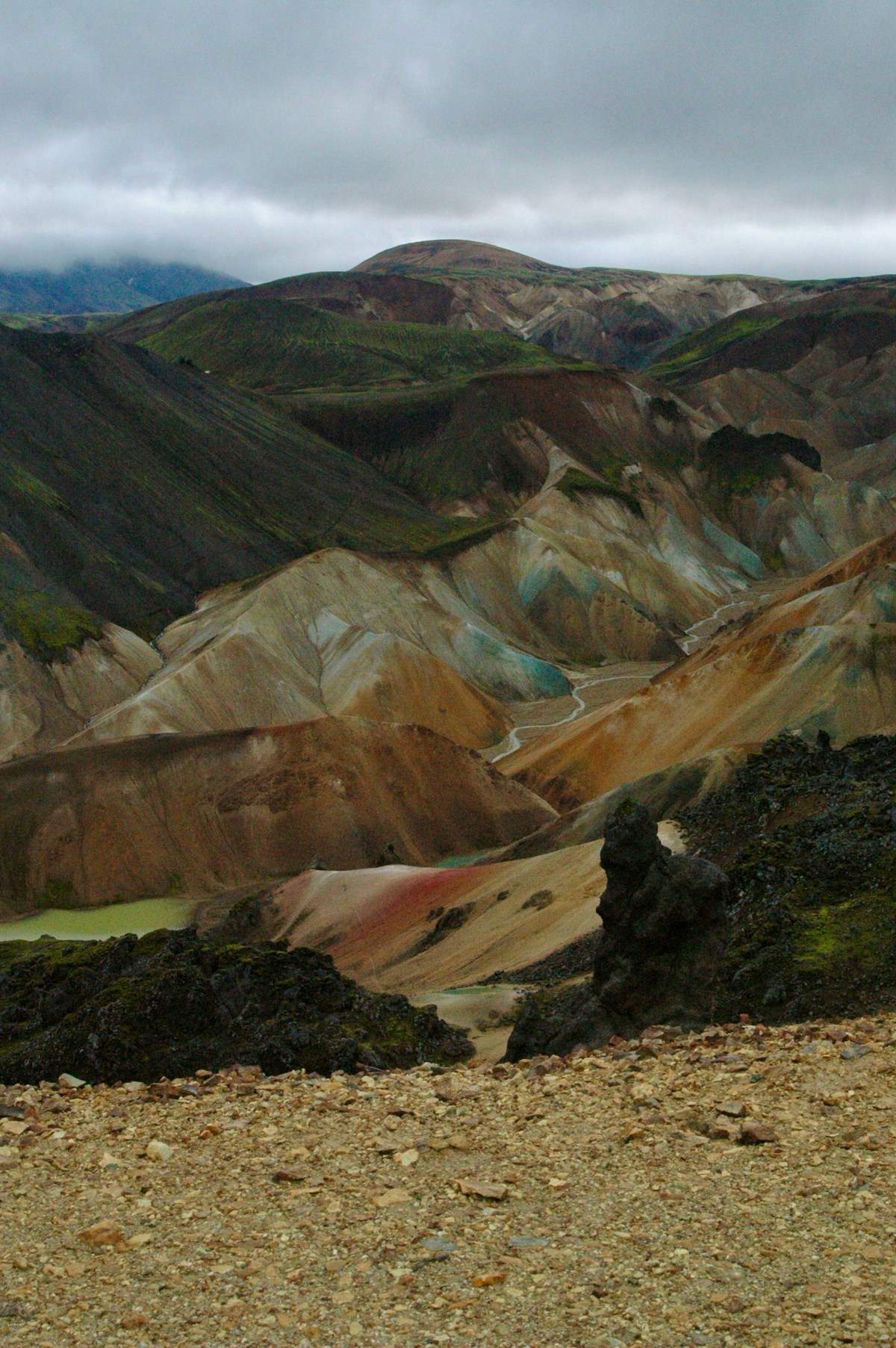 Trekkers on a colourful Highland trail in Iceland with geothermal steam rising in the background