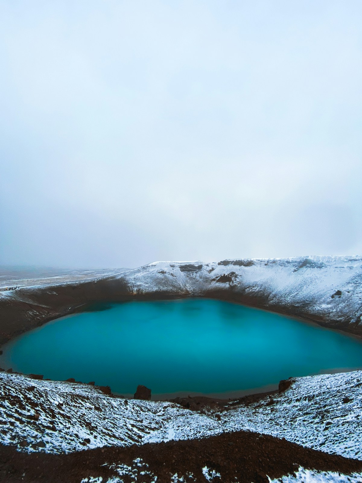 Turquoise Víti crater lake at Krafla surrounded by snow-capped volcanic ridges, near Lake Mývatn, Iceland