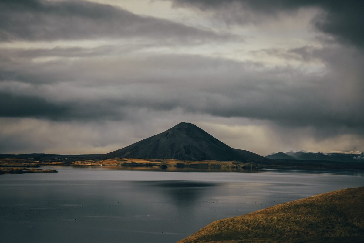 Mount Vindbelgjarfjall reflected in calm Lake Mývatn under dramatic clouds, north Iceland