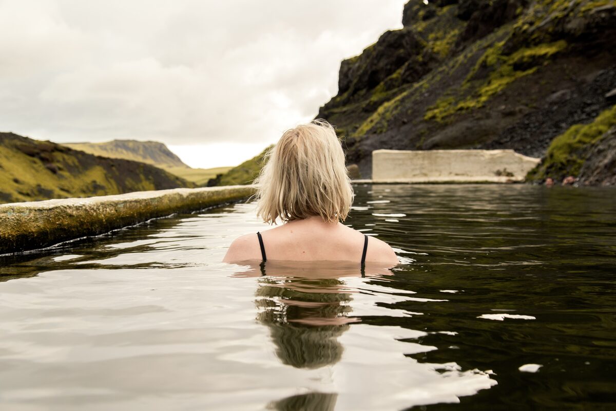 Woman relaxing in a natural geothermal pool surrounded by Icelandic volcanic mountains