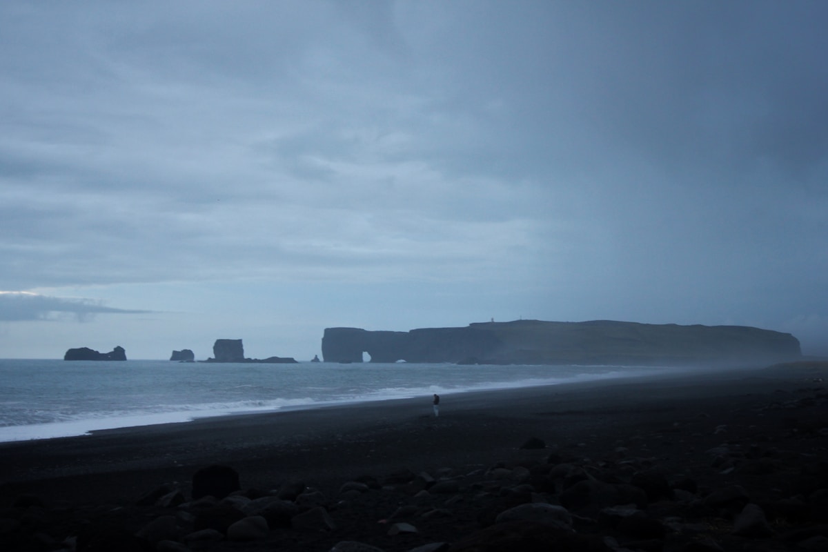 Foggy black sand beach at Reynisfjara with Dyrhólaey arch and sea stacks, Vík, Iceland