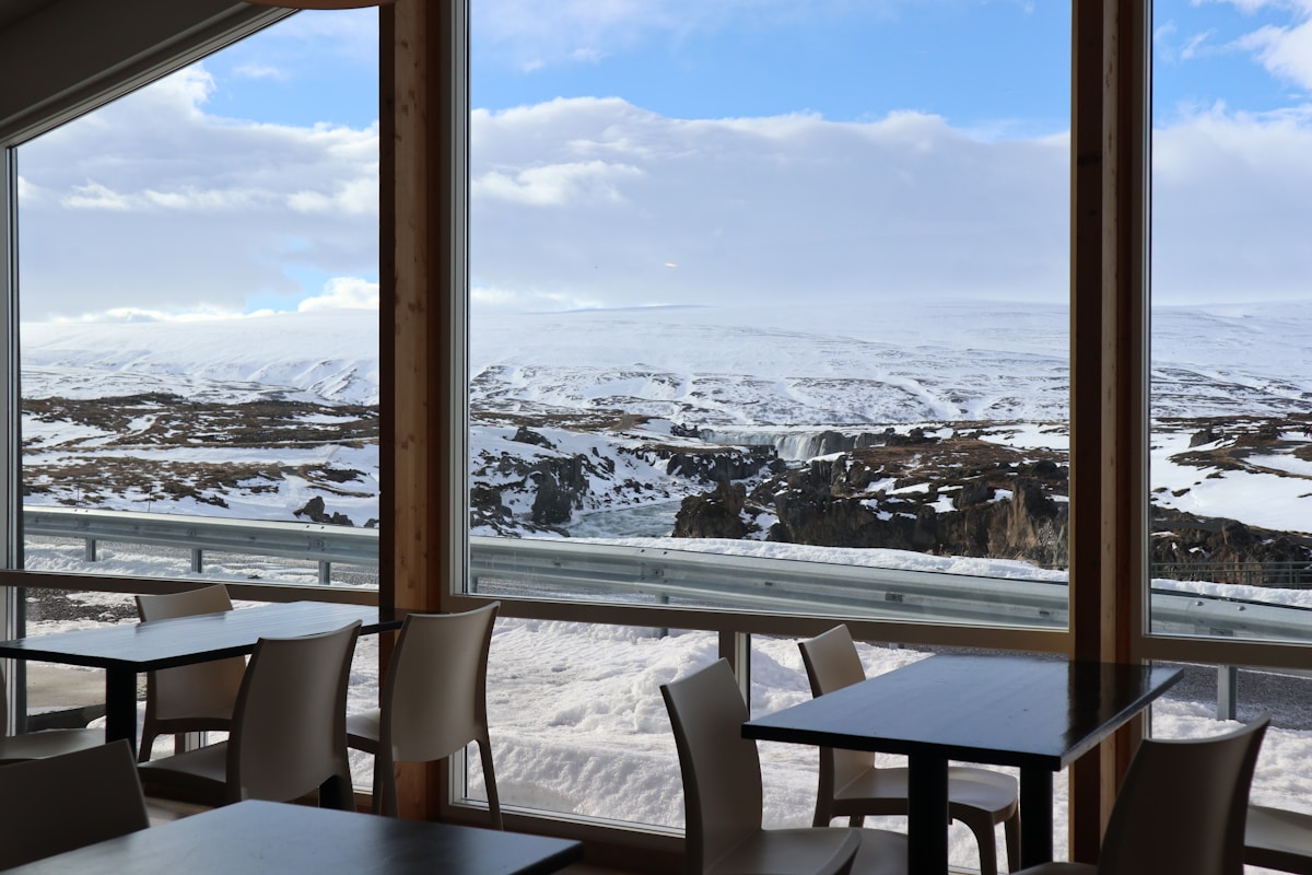 Restaurant interior with floor-to-ceiling windows looking out over a snowy Icelandic landscape