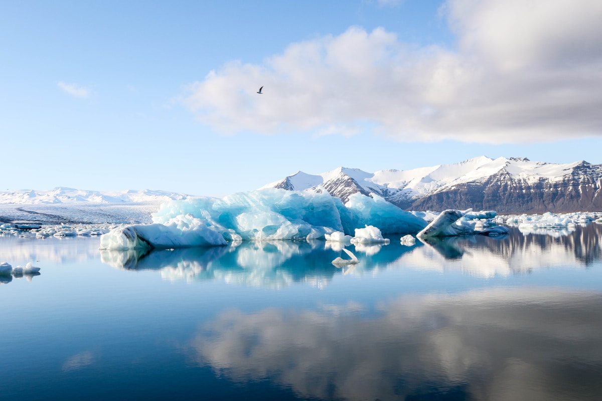 Icebergs and alpine mountains reflected in calm water at Jökulsárlón Glacier Lagoon near Höfn, Iceland