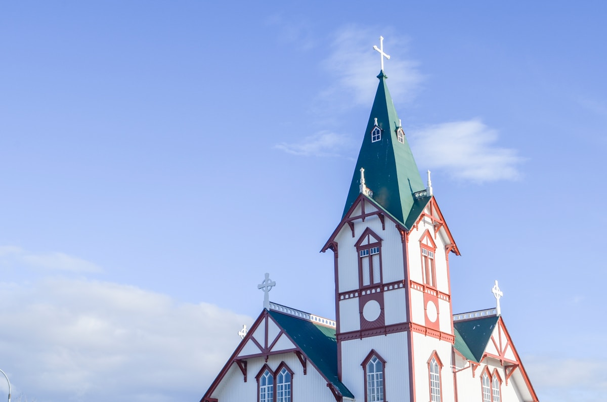 White and red church with a green steeple in Húsavík, north Iceland