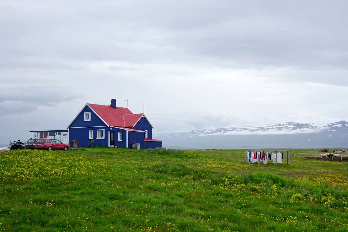 Red and white guesthouse on green grass field, Husey, north Iceland