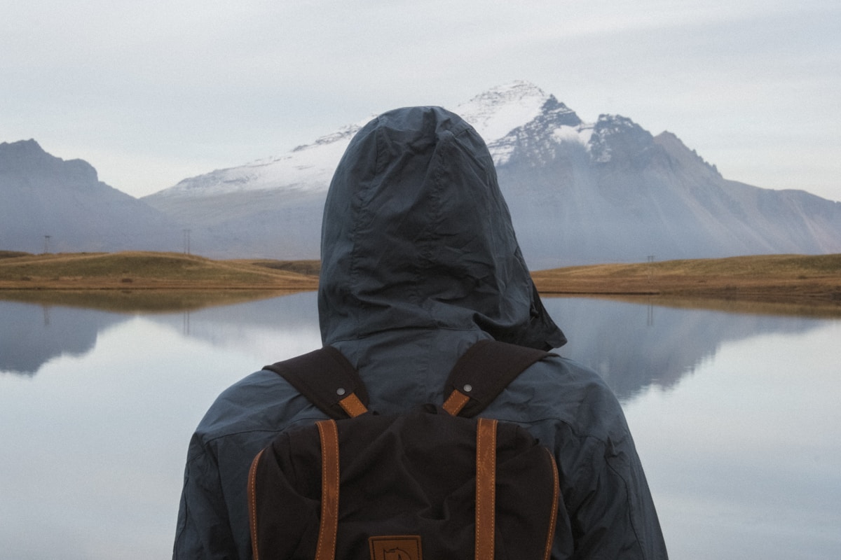 Hiker with backpack standing near a body of water, Iceland outdoor adventure