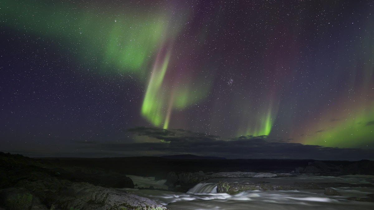 Northern Lights over Iceland's black sand coast and dramatic Arctic fjord scenery