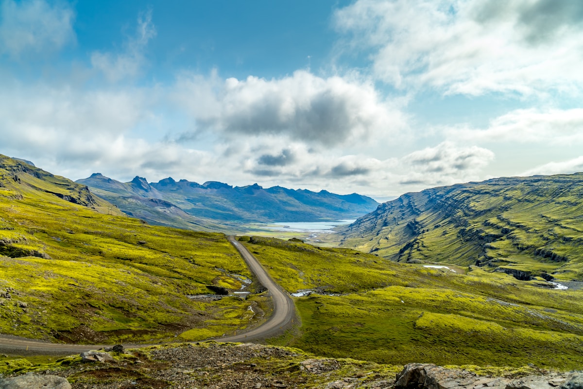 Green grass field and mountain under bright blue sky and white clouds, Iceland summer landscape