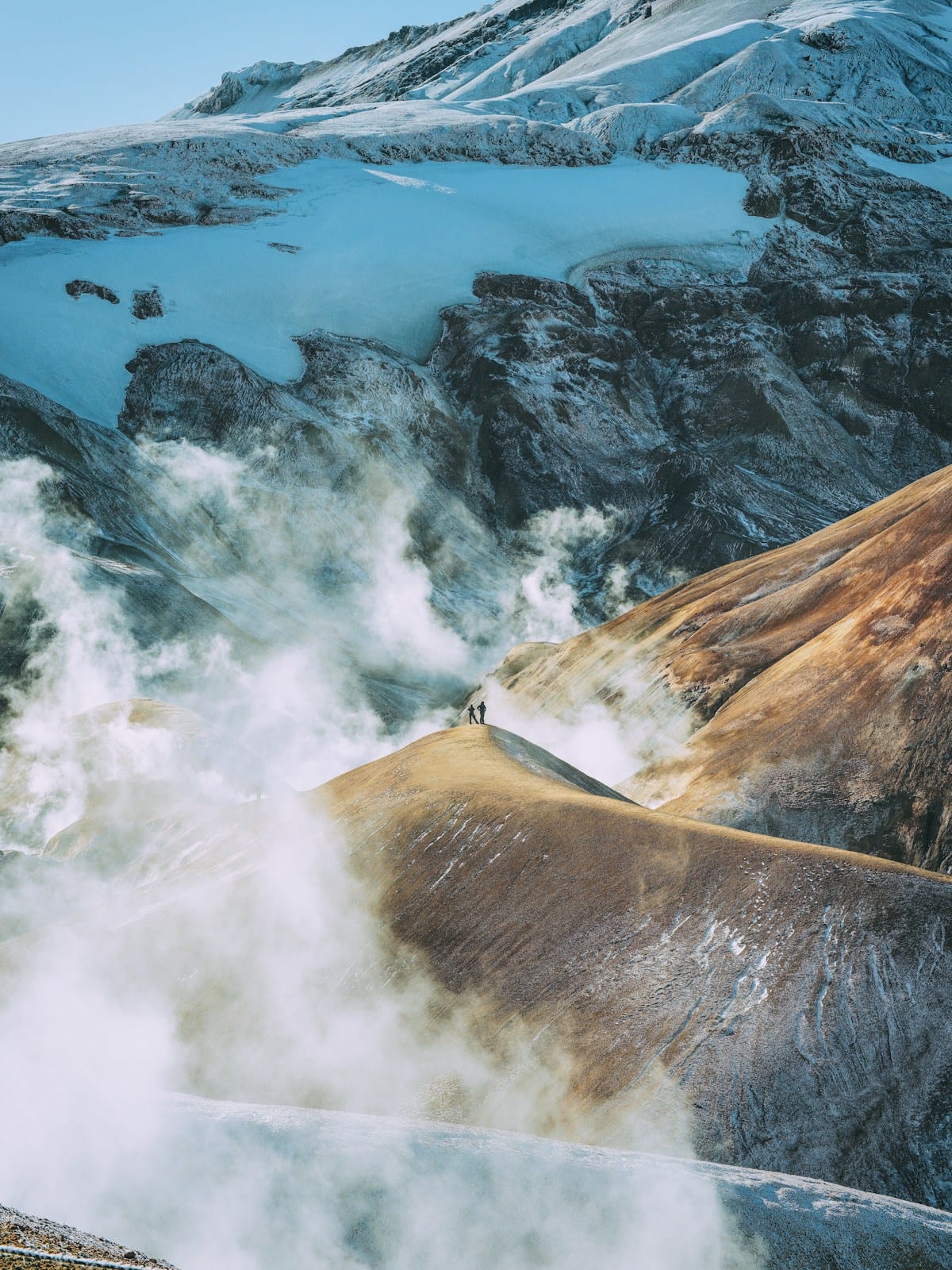 Two hikers on a geothermal ridge above steam vents at Kerlingarfjöll, Iceland