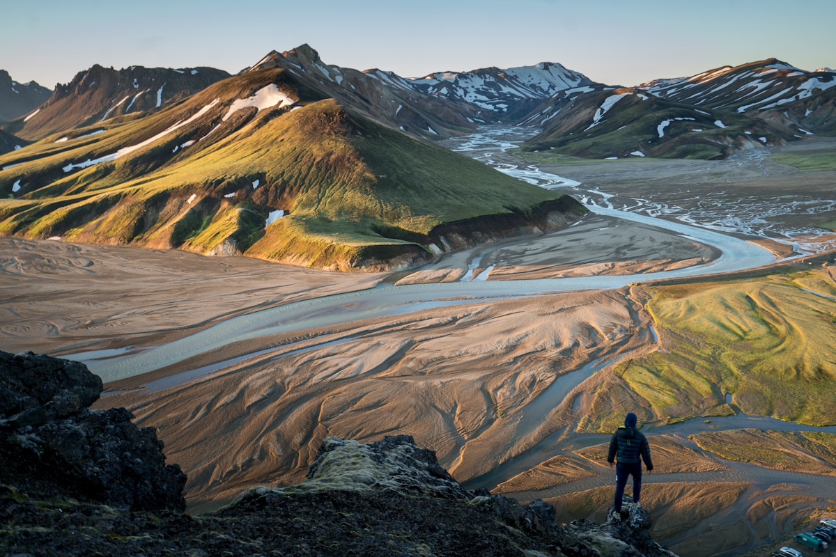 Hiker standing on edge of cliff at Landmannalaugar, Iceland — August