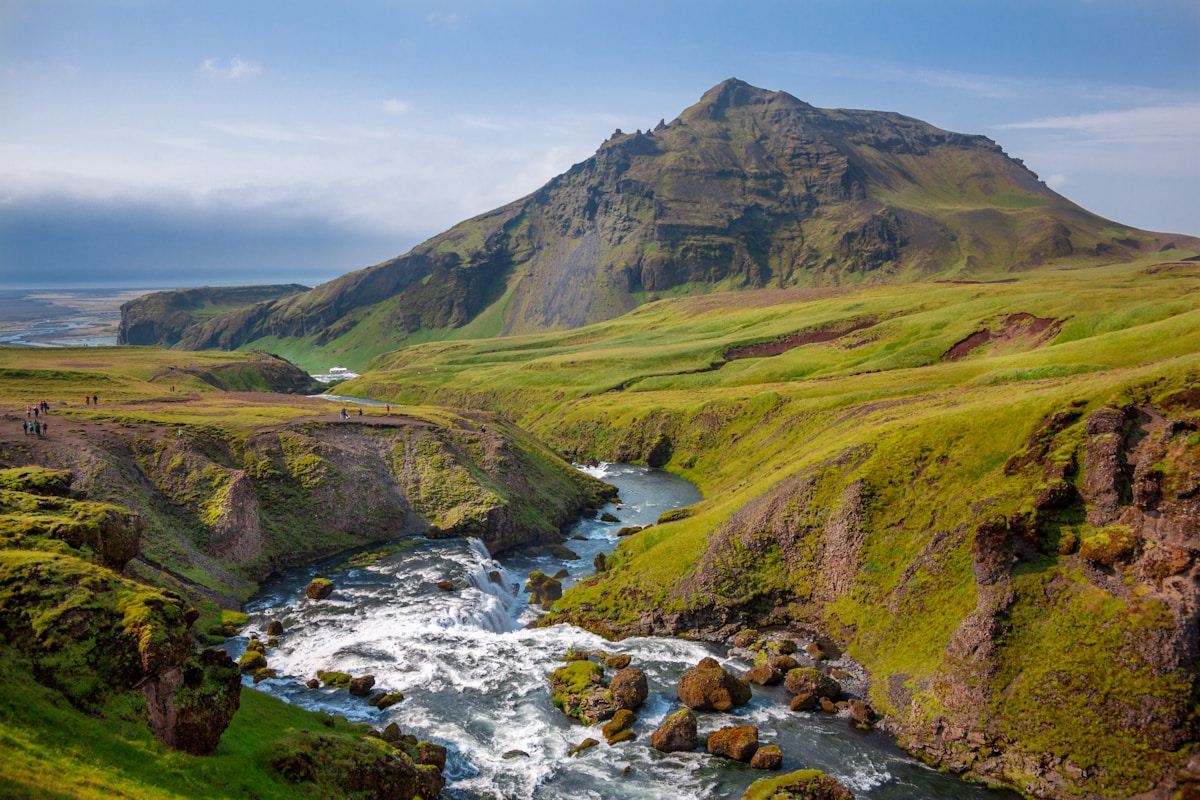 River and green grass covered mountain near Skógafoss, Iceland — July
