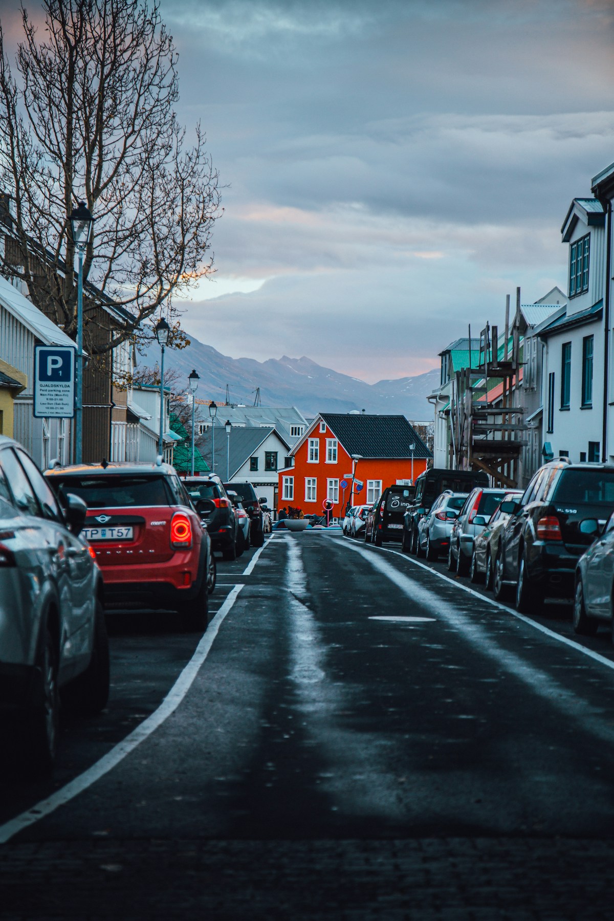 Street lined with cars, houses, and mountains in the distance, Reykjavik, Iceland