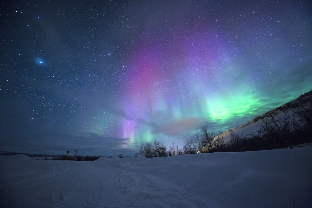 Aurora borealis with green and purple lights over a snowy Iceland landscape at night