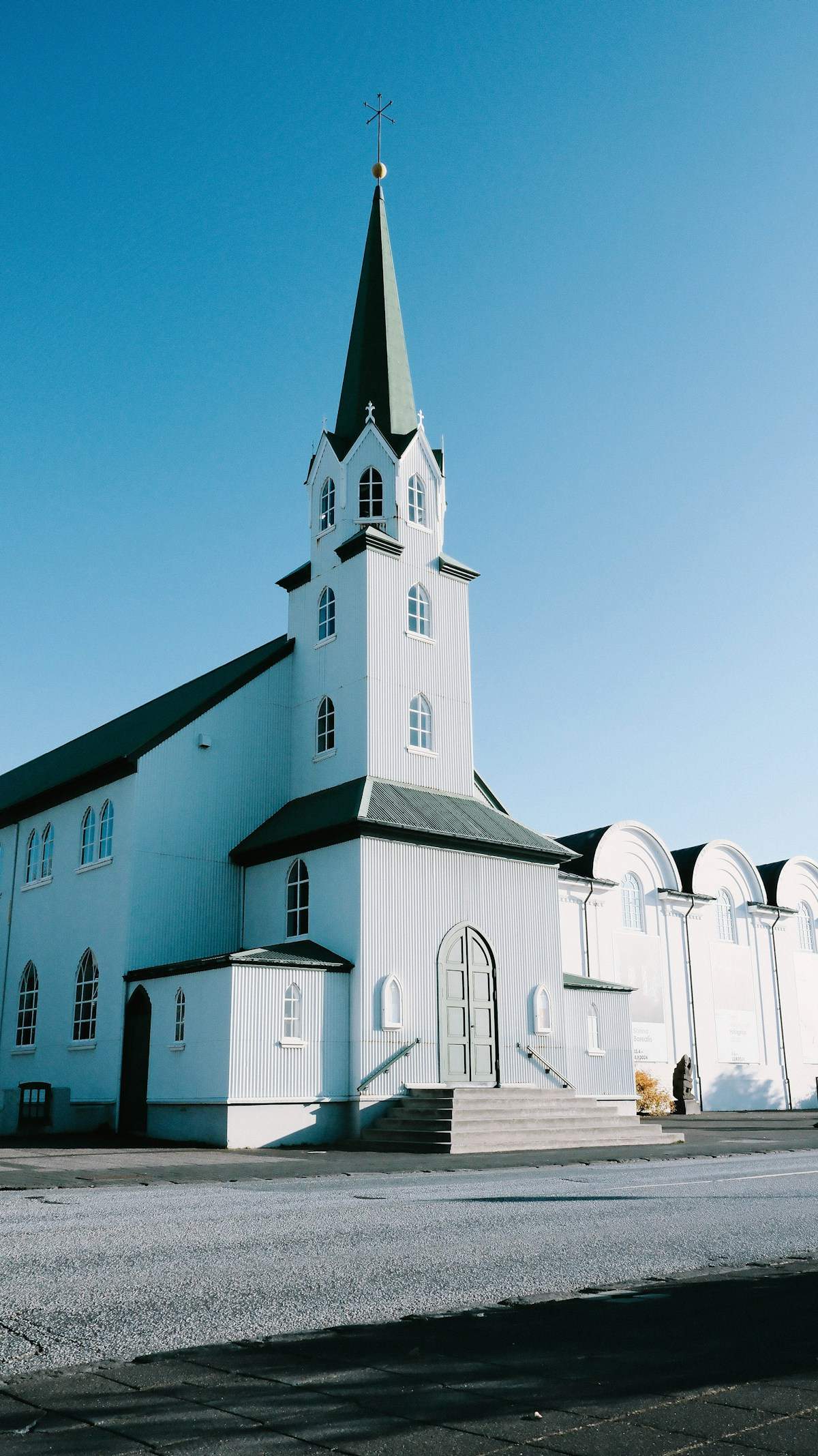 White Reykjavik Free Church with a dark steeple under a clear blue sky, Reykjavik, Iceland