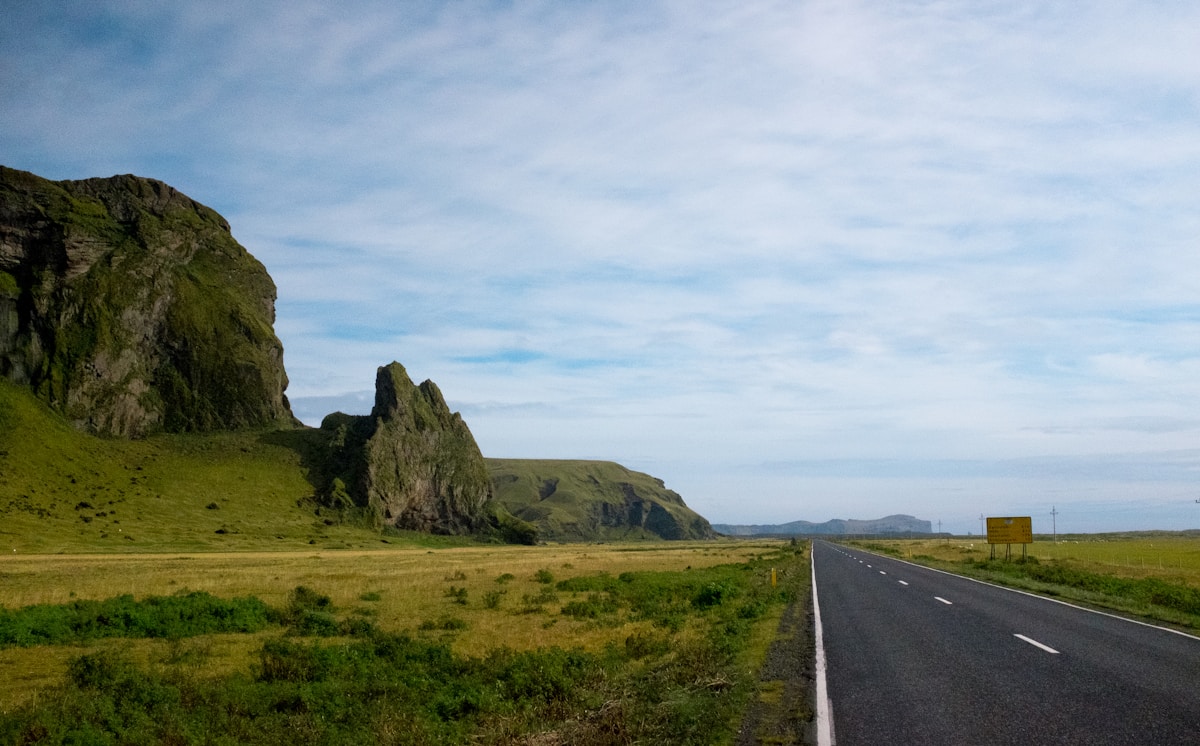 Grey concrete road near green grass field in south Iceland countryside