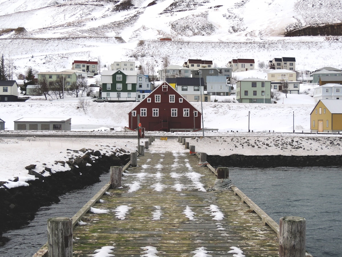 Wooden dock leading to colourful houses at Siglufjörður harbour, north Iceland fjord