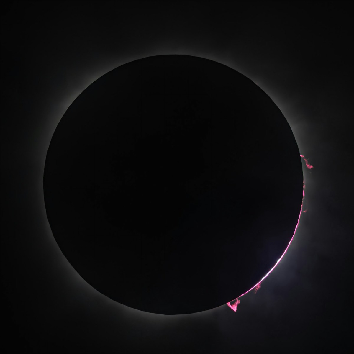 Total solar eclipse with the sun's corona visible around the dark disc of the moon
