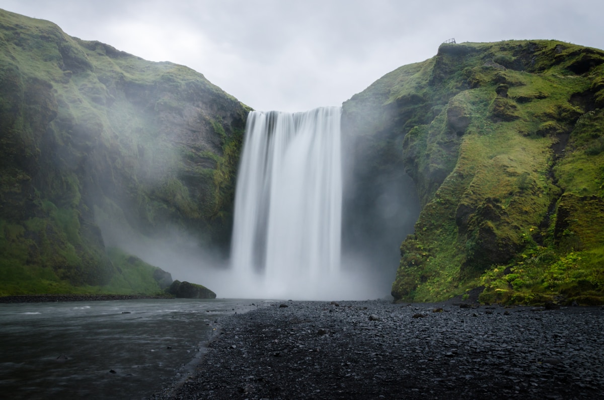 Skógafoss waterfall cascading over green cliffs on Iceland's south coast
