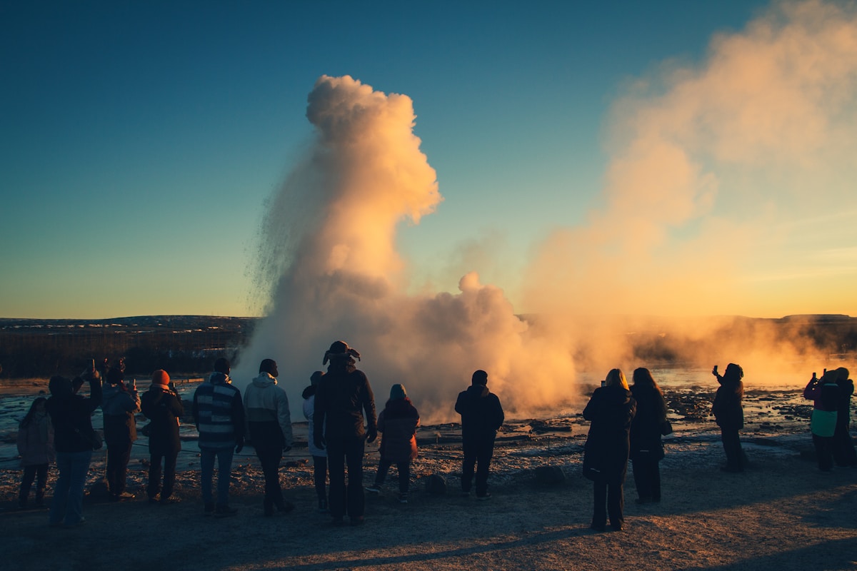 Crowd watching Strokkur geyser erupt at sunset at Geysir, Golden Circle Iceland