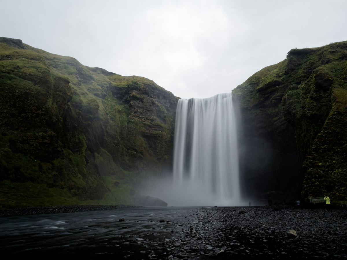 Skógafoss waterfall in Iceland with black basalt rocks and misty spray