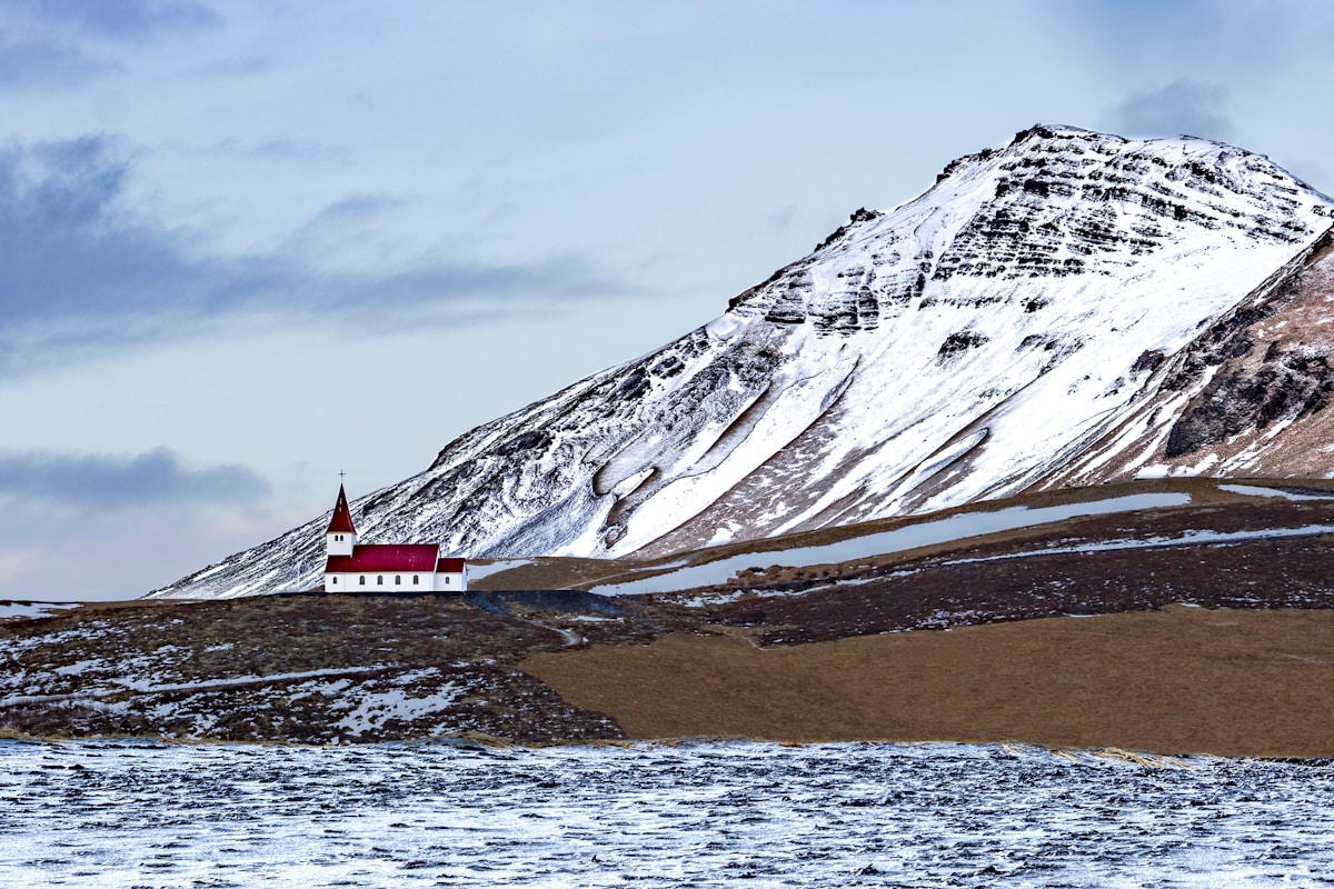 White and brown house near a snow-covered mountain in Vík, south Iceland
