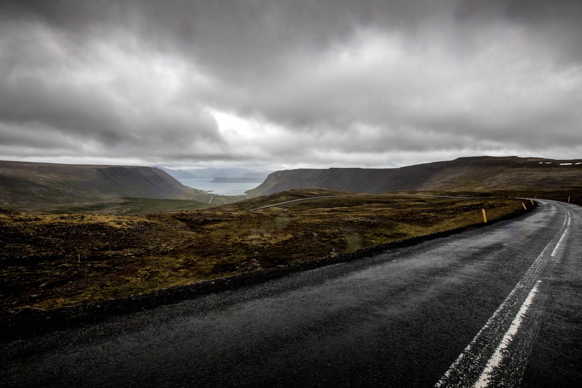 Grey asphalt road winding through dramatic fjord landscape, Westfjords Region, Iceland