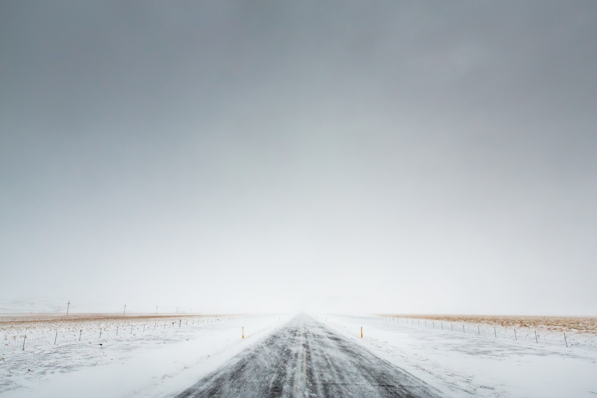 Car driving on a snow-covered road in Iceland with mountains in winter light
